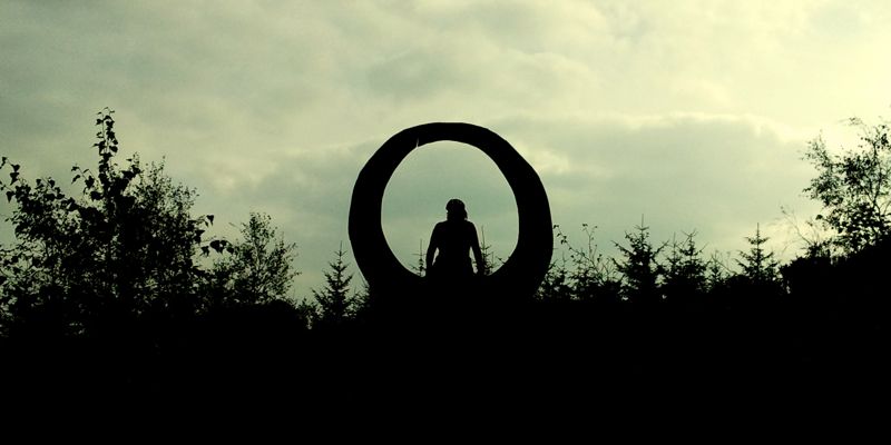 woman eclipsed by circular sculpture